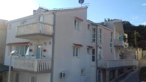 a white building with balconies on the side of it at Apartments Muic in Tisno