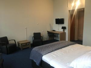 een hotelkamer met een bed en twee stoelen en een bureau bij Hotel Wilhelmina in Venlo