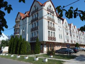 a large white building with cars parked in a parking lot at Oli Apartman in Hajdúszoboszló