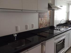 una cocina con encimera negra y fregadero en Apartamento aconchegante próximo ao shopping Beira Mar, en Florianópolis