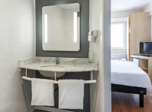 a bathroom with a sink and a mirror and a bed at ibis Tambore in Barueri