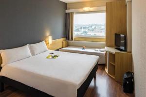 um quarto de hotel com uma cama grande e uma televisão em ibis Tambore em Barueri