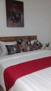 1 cama con almohadas y manta roja y blanca en Anugrah Jaya Guest House, en Canggu