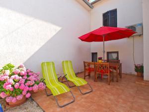 House Sandra 1430 في Peresiji: فناء مع طاولة وكراسي ومظلة حمراء