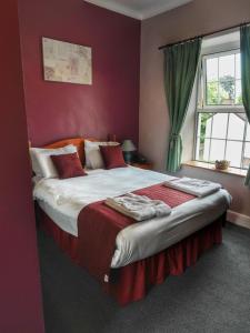 a bedroom with a large bed with red walls at The Fountain Inn in Parkend