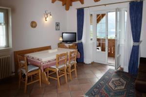 comedor con mesa, sillas y TV en Casa Rubino Lake & Dolomites, en Molveno