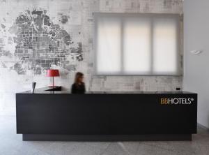 a woman sitting at a reception desk in an office at BB Hotels Aparthotel Isola in Milan