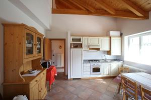una cocina con electrodomésticos blancos y armarios de madera en Casa Rubino Lake & Dolomites, en Molveno