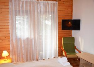 a room with a window with a green chair and a television at Zajazd Beskidy in Żywiec