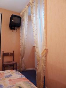 um quarto com uma cama, uma televisão e cortinas em Hôtel Restaurant du Pont-Vieux em Saint-Flour