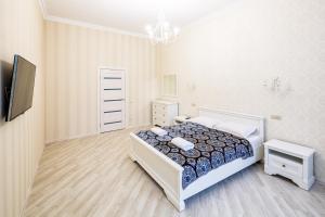 リヴィウにあるLEOGRAND VIP Apartments on Udatnogo 4の白いベッドルーム(ベッド1台、テレビ付)