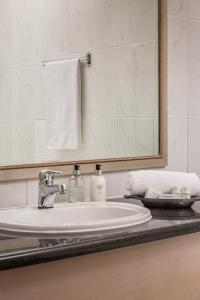 a white sink sitting under a mirror in a bathroom at Cape Town Beachfront Apartments at Leisure Bay in Cape Town