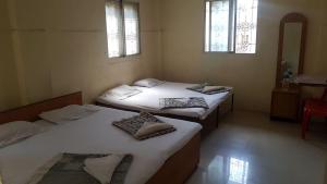 two beds in a room with two windows at Godavari Lodge in Solapur