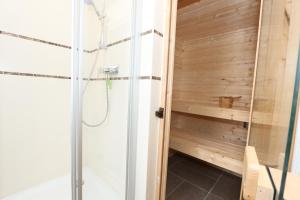 a shower in a bathroom with a wooden wall at Haus Seestern in Thiessow
