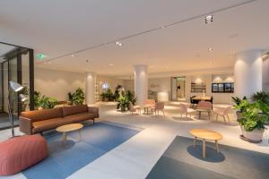 a lobby with a couch and tables and chairs at PREMIER SUITES PLUS Rotterdam in Rotterdam