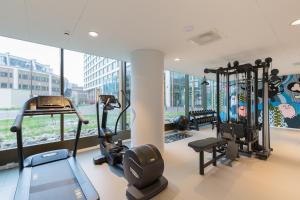 een fitnessruimte met cardio-apparatuur in een gebouw met ramen bij PREMIER SUITES PLUS Rotterdam in Rotterdam