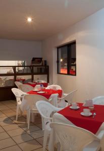 a restaurant with tables and white chairs with red table cloth at Hotel Kyoto in Puebla