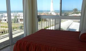 a bedroom with a large window with a view of a lighthouse at Perla del Este in La Paloma