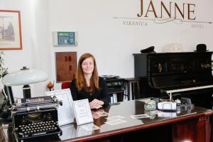 una mujer sentada en un escritorio con una máquina de escribir en Janne Hotel en Riga