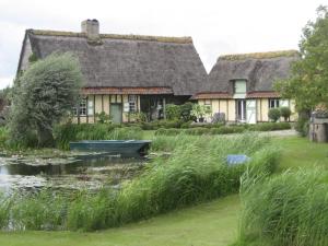 a house with a pond and a boat in front of it at Sint-Coryn in Reninge