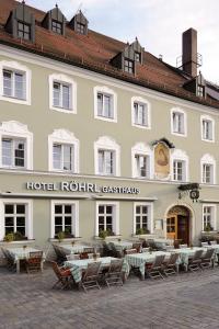 een hotel met tafels en stoelen voor een gebouw bij Hotel & Gasthaus DAS RÖHRL Straubing in Straubing