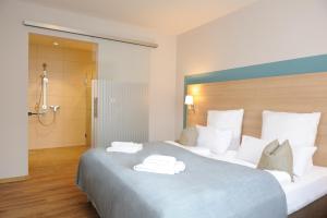 
a hotel room with a bed, desk, and mirror at Hotel & Gasthaus DAS RÖHRL Straubing in Straubing
