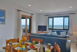 a living room with a table and a blue couch at Front Line Beach Apartment in Son Serra in Son Serra de Marina
