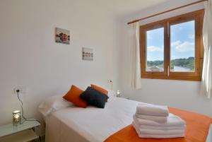 a white bedroom with a bed with a window at Front Line Beach Apartment in Son Serra in Son Serra de Marina