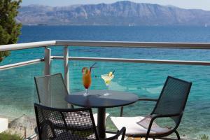 a table with two drinks on a balcony overlooking the ocean at Porto Galini Seaside Resort & Spa in Nikiana