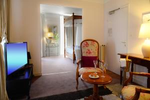 a living room with a television and a room with a bed at Logis Hôtel et Restaurant du Dauphin in Sées