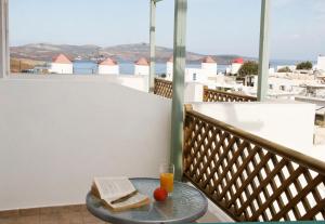 un vaso de zumo de naranja y un libro sobre una mesa en un balcón en Atlantic, en Astipalea
