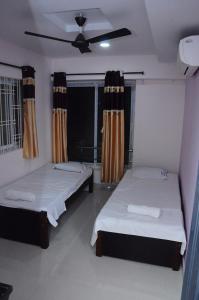een slaapkamer met 2 bedden en een plafondventilator bij SGS Residency in Tirupati
