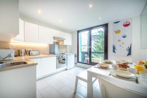 eine Küche mit weißen Geräten und einem Tisch mit Stühlen in der Unterkunft Rupicapra apartment - Chamonix All Year in Chamonix-Mont-Blanc
