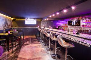 a bar with stools in a room with purple lighting at PLAZA INN stays design Dortmund in Dortmund