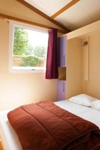 1 dormitorio con 1 cama grande y ventana en Camping De La Plage Bénodet - 400 mètres de La Plage, en Bénodet