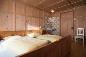 Cama grande en habitación con paredes de madera en Chasa Anguel, en Samnaun