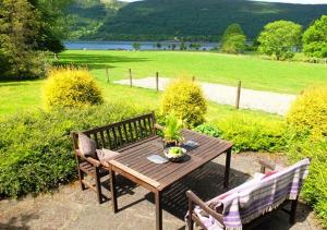 a wooden table and two benches sitting next to a field at Ardno Cottage by Loch Fyne in Cairndow