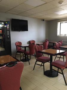 une salle à manger avec des tables, des chaises et une télévision dans l'établissement Floral Park Motor Lodge, à Floral Park