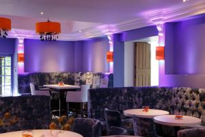 a dining room with purple walls and tables and chairs at Forrester Park Resort in Dunfermline