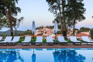 a group of chairs and umbrellas next to a swimming pool at Santiago Hotel in Santiago do Cacém