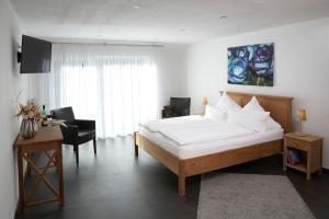 ein Schlafzimmer mit einem großen Bett und einem Schreibtisch mit einem Stuhl in der Unterkunft Hotel Restaurant Daute in Iserlohn