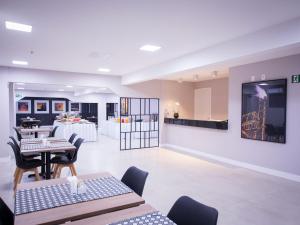 a dining room with tables and chairs and a kitchen at Vila Business Hotel in Volta Redonda