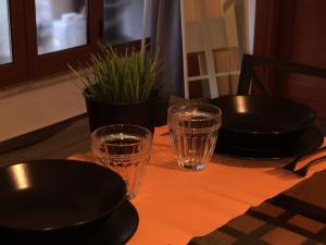a table with two glasses and plates and a plant at palermo casa vacanze in Palermo