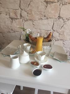 a white table with bowls and cups and a yellow vase at Au charmant des vignes in Montagne