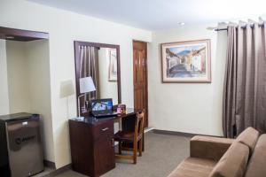 a room with a desk with a computer and a couch at Hotel Cajamarca in Cajamarca