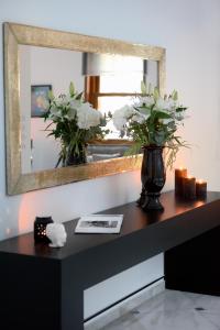 une table avec un miroir et un vase avec des fleurs dans l'établissement ALDIS MANSION by K&K, à Athènes