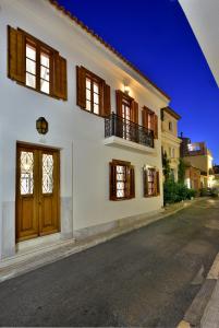- un bâtiment blanc avec des portes et des fenêtres en bois dans l'établissement ALDIS MANSION by K&K, à Athènes
