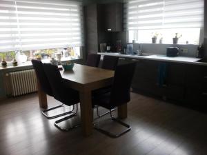 una cucina con tavolo in legno e sedie nere di Kamer + douche in villa a Knokke-Heist