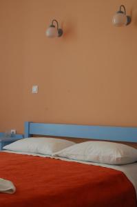 a bed with a blue headboard and two white pillows at Hotel Paros in Parikia