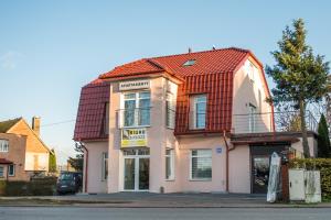 a pink house with a red roof on a street at METRAK Apartamenty Darlowo in Darłowo